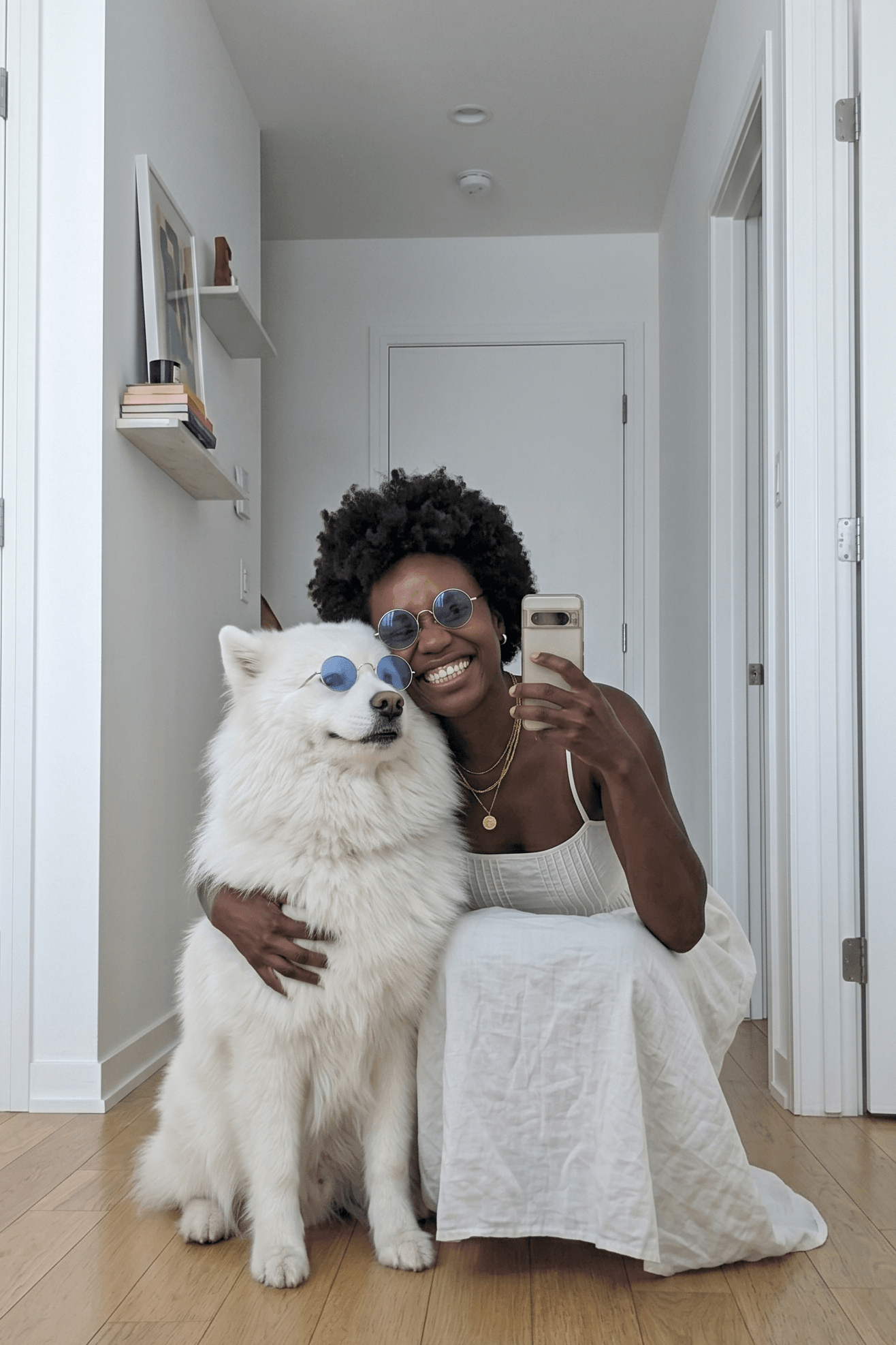 Woman taking a selfie with a white dog in a hallway