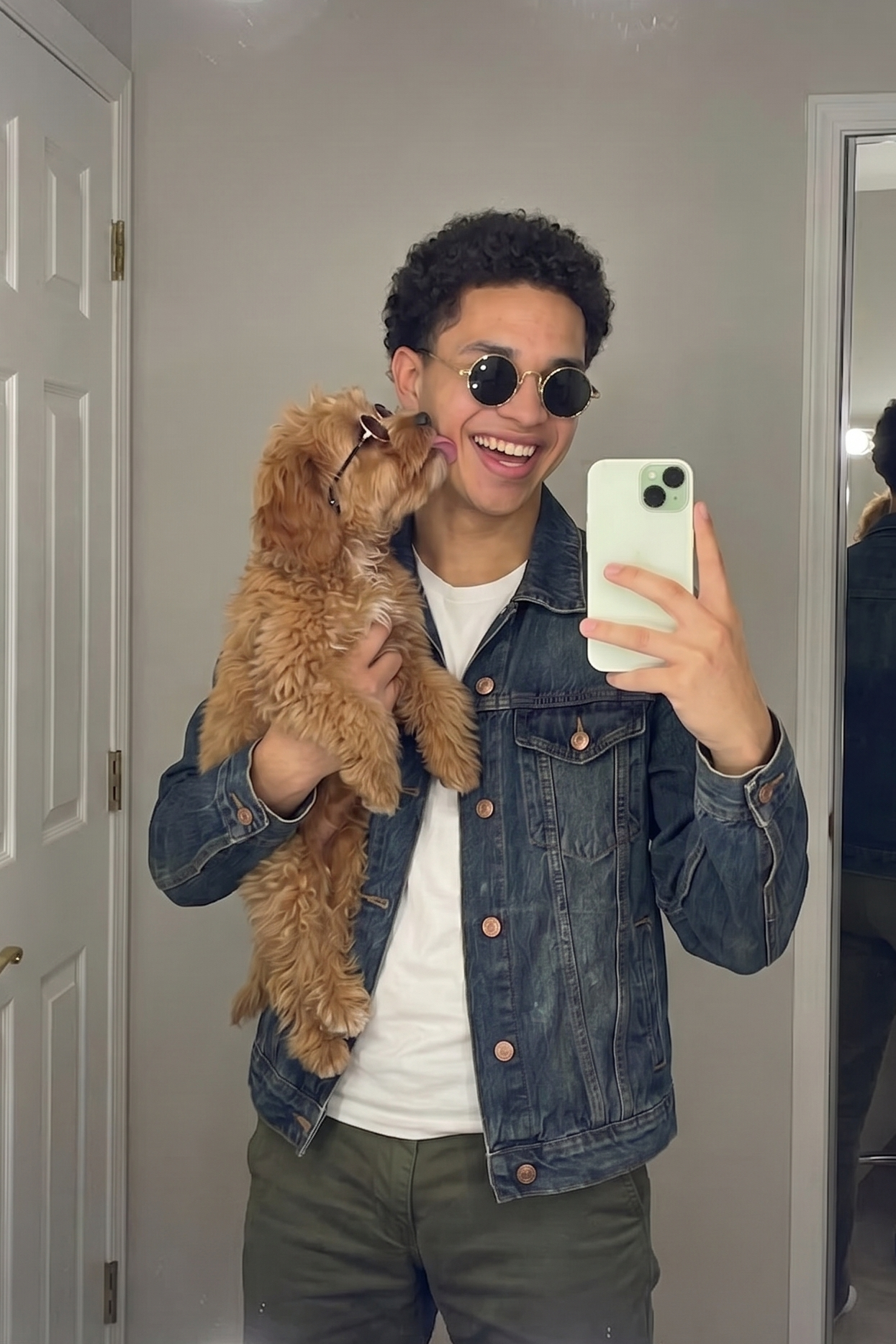 man in denim jacket hold small dog wearing sunglasses
