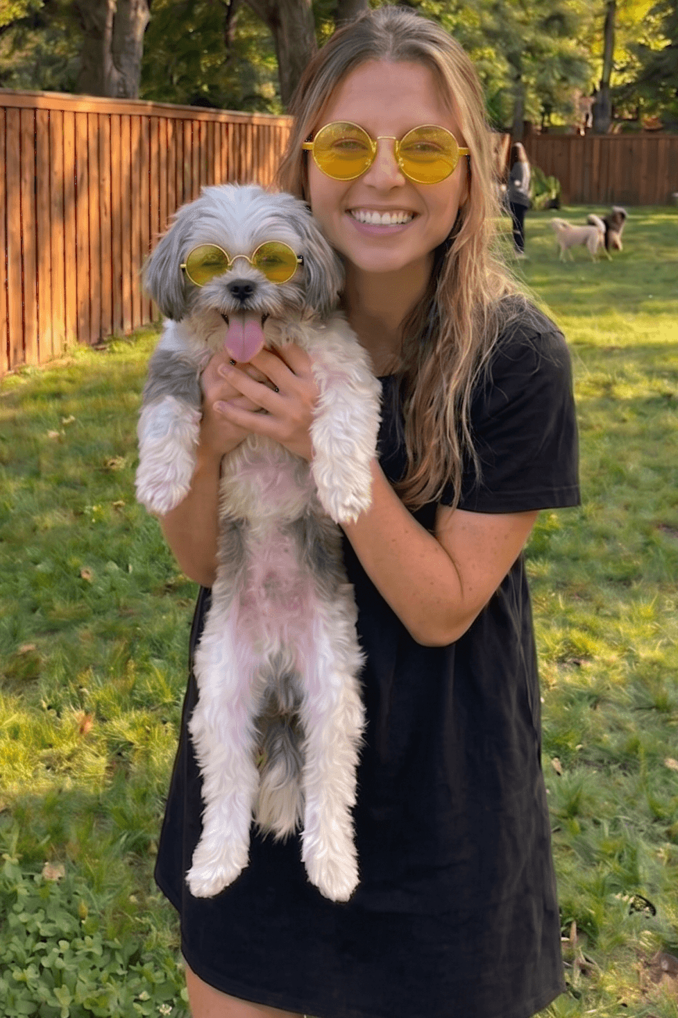 Woman holding a small dog in a backyard