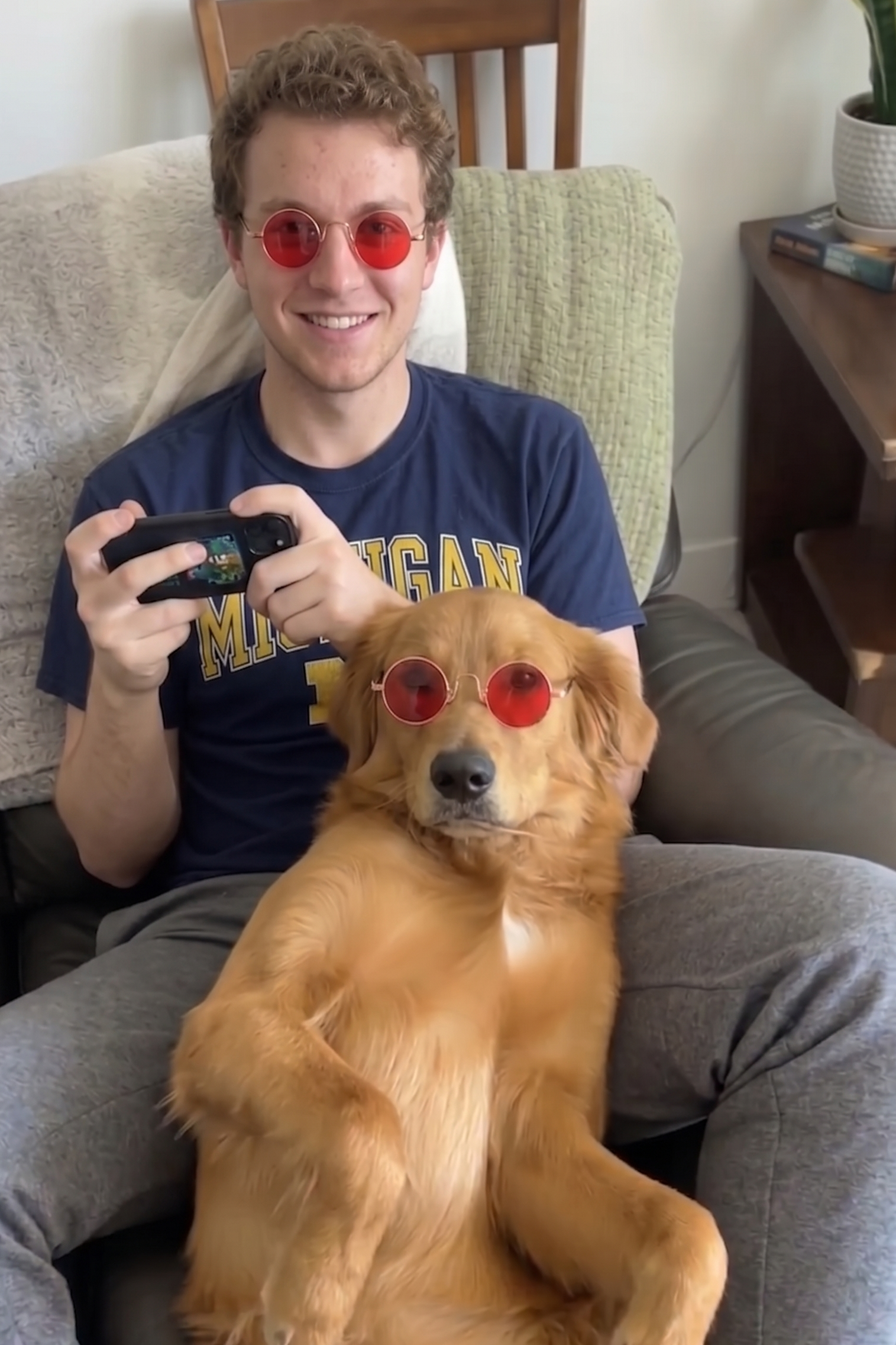 Person and dog wearing red sunglasses sitting on a couch